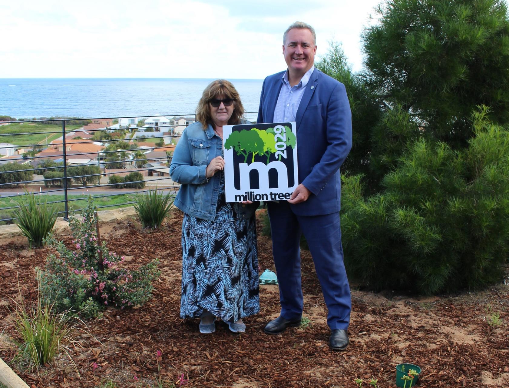 City of Greater Geraldton Mayor Shane Van Styn and Veronica Foster amidst some of the 50 trees and shrubs she planted, registered with the Million Trees project and reached the 500,000th planting milestone.